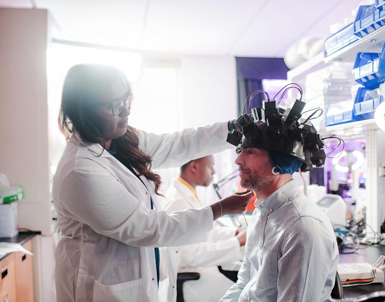 Dr. Murugan fitting photon-sensing helmet on research subject